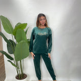 Woman in a dark green velvet PJ set with a Special One gold print top and jogger pants