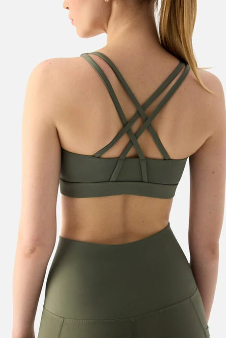 Person wearing a green sports bra and leggings on a white background