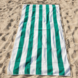 Green and white striped beach towel on sand with 75x140 cm size measurements