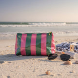 Striped pouch on a sandy beach with sunglasses and sunscreen