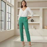 Person wearing a white blouse and green pants in a modern room