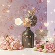 Charcoal figure with gold spots, her lit glass globe glowing against floral wallpaper