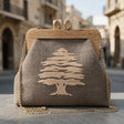 Grey brown cedar clutch with a wooden frame clasp and gold chain on a stone street in an old Lebanese town