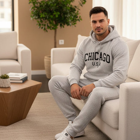 Man wearing a grey 'Chicago USA' hoodie and sweatpants sitting on a couch in a modern living room