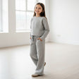 Girl in a grey sweatshirt and matching wide leg pants with pockets