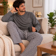 Man relaxing on a sofa with a mug in a grey textured top and black and white gingham pyjama trousers