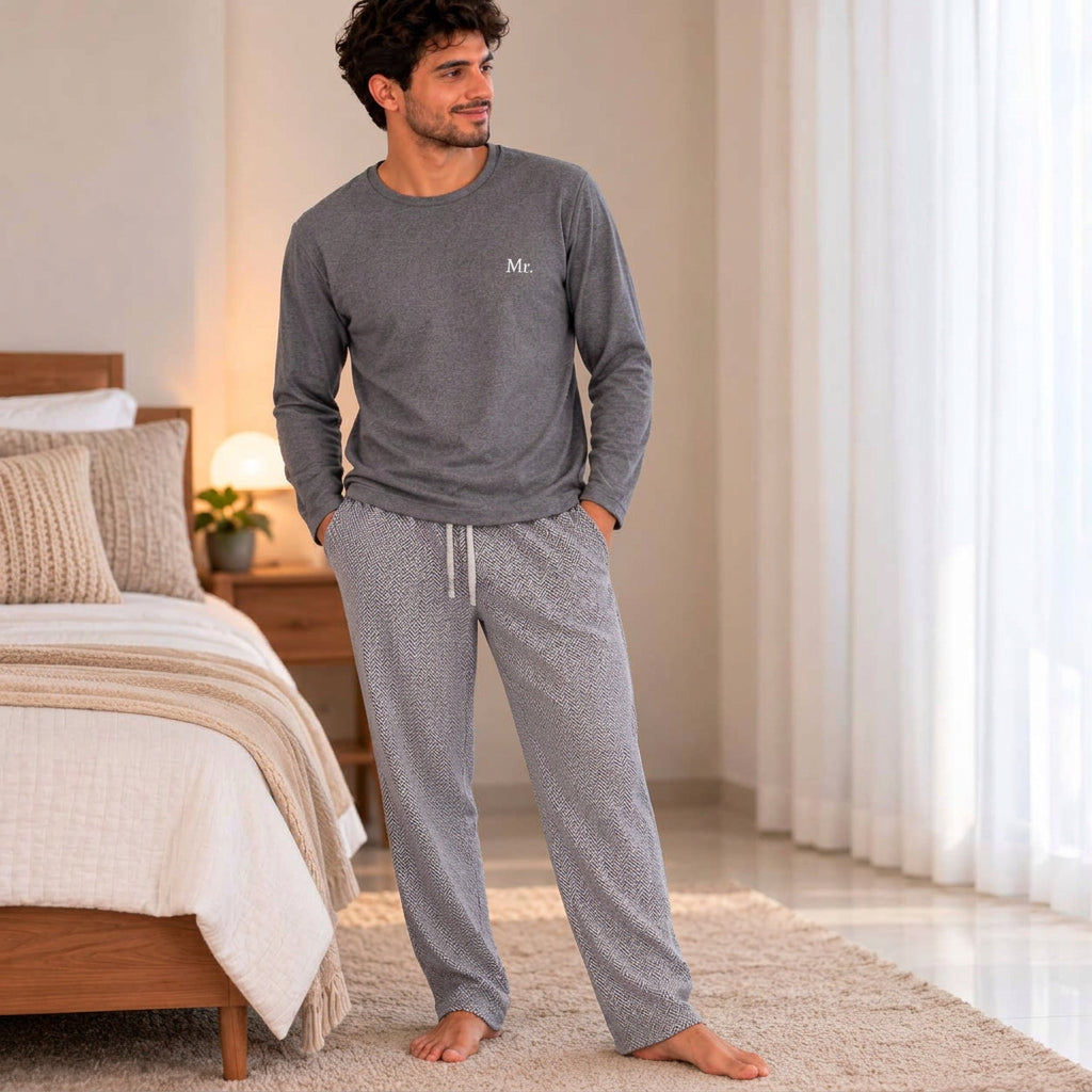 Standing in a bedroom wearing a grey long sleeve pyjama top and drawstring herringbone bottoms