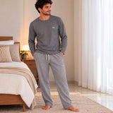Standing in a bedroom wearing a grey long sleeve pyjama top and drawstring herringbone bottoms