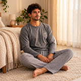 Man sitting on a cream rug in a charcoal top with chest script and light grey textured trousers