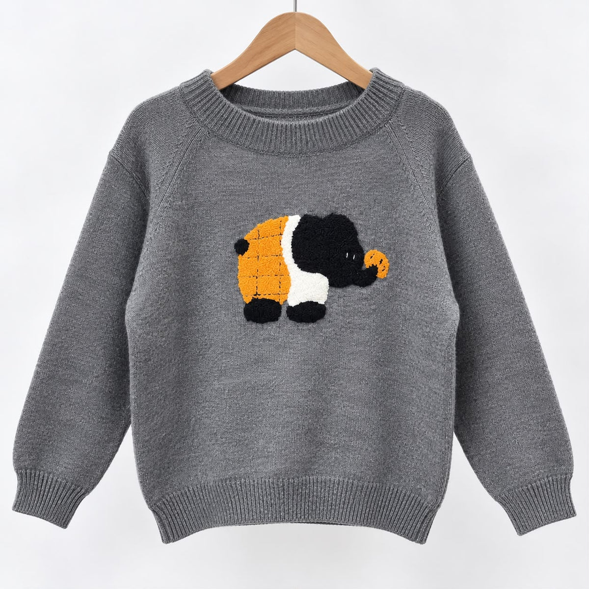 Grey knit sweater on a wooden hanger with a fluffy black, white and orange elephant patch