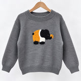 Grey knit sweater on a wooden hanger with a fluffy black, white and orange elephant patch