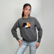 Grey knit sweater with a fuzzy black, white and orange elephant patch, hands on hips