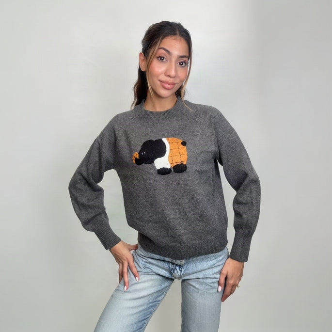 Grey knit sweater with a fuzzy black, white and orange elephant patch, hands on hips
