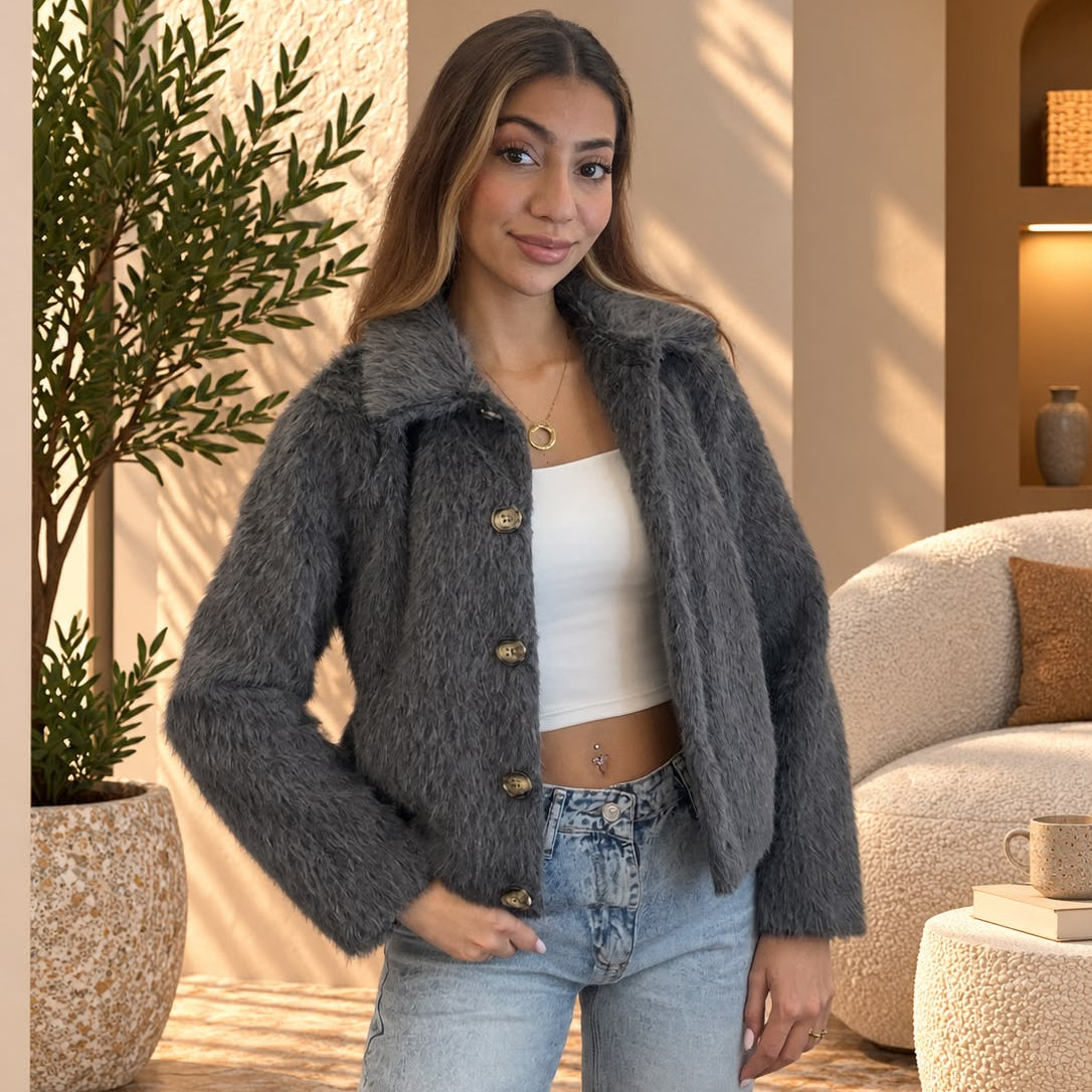 Grey cropped faux fur jacket worn open over a white crop top and jeans