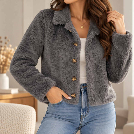 Grey faux fur jacket with a wide collar and four bronze buttons, worn open over a white tank