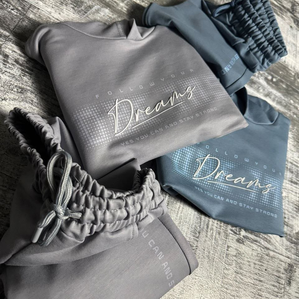 Grey Dreams hoodie and joggers folded on a wooden floor