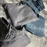Grey Dreams hoodie and joggers folded on a wooden floor