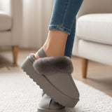 Dove grey platform slipper with a taupe fur collar, worn on tiptoe on a textured rug