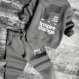 Grey sweatshirt laid flat showing the back print above matching joggers