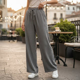 Person wearing gray wide-leg pants standing on a street with blurred background