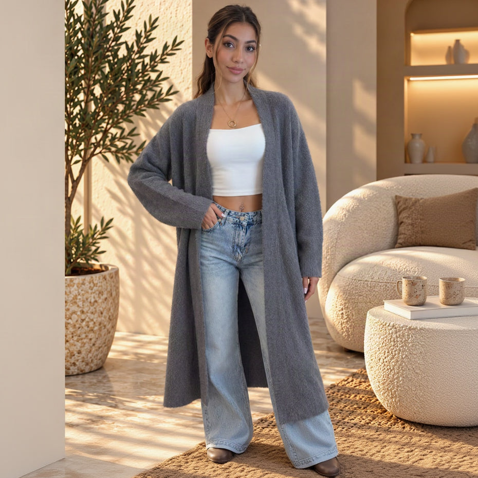 Knee length grey open front coat with a shawl collar and long sleeves, hand in jeans pocket