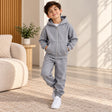 Boy in a grey marl zip up hoodie and matching grey joggers in a living room