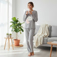 Grey fleece pyjama set with a cloud and pink moon applique, worn standing while holding a mug