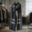 Heather grey scarf with black and light grey plaid bands looped around a hanger
