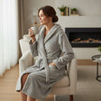 Woman in an armchair by a fireplace wearing a grey plush hooded robe