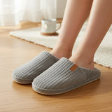 Grey ribbed slippers worn on bare feet showing the small leather tab at the collar