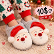 Pale grey plush kids slippers with embroidered Santa faces worn with Christmas tree print pyjamas