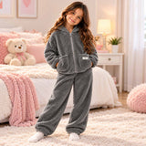 Grey sherpa fleece kids pajama set with zip up jacket and matching pants in a cozy bedroom