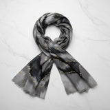 Grey scarf with black and gold pattern on a white background
