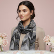 Woman wearing a grey patterned scarf with pink roses in the background