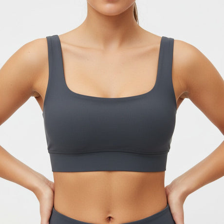 Person wearing a grey sports bra and leggings on a light grey background