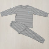 Grey and white stripe kids pyjama set laid flat on a wood floor, crew neck top with cuffed joggers