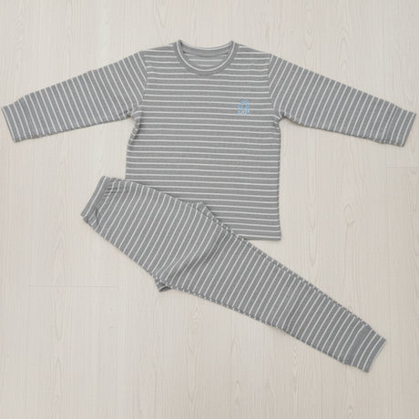 Grey and white stripe kids pyjama set laid flat on a wood floor, crew neck top with cuffed joggers