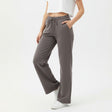 Woman wearing grey pants and a white top on a white background