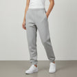 Person wearing grey sweatpants and white sneakers on a plain background