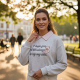 Woman wearing a grey marl collared sweatshirt with a pink embroidered teddy bear