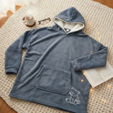 Slate grey hooded blanket laid flat on a knitted rug showing the bear motif and pocket