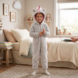 Girl standing in a grey fluffy unicorn onesie with pink horn and rainbow mane hood