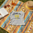 Tank top with 'CAPABILITY 92' text on a colorful blanket with a book, sunglasses, and hat.