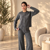 Grey knit zip cardigan and wide leg trousers set, hand at hair