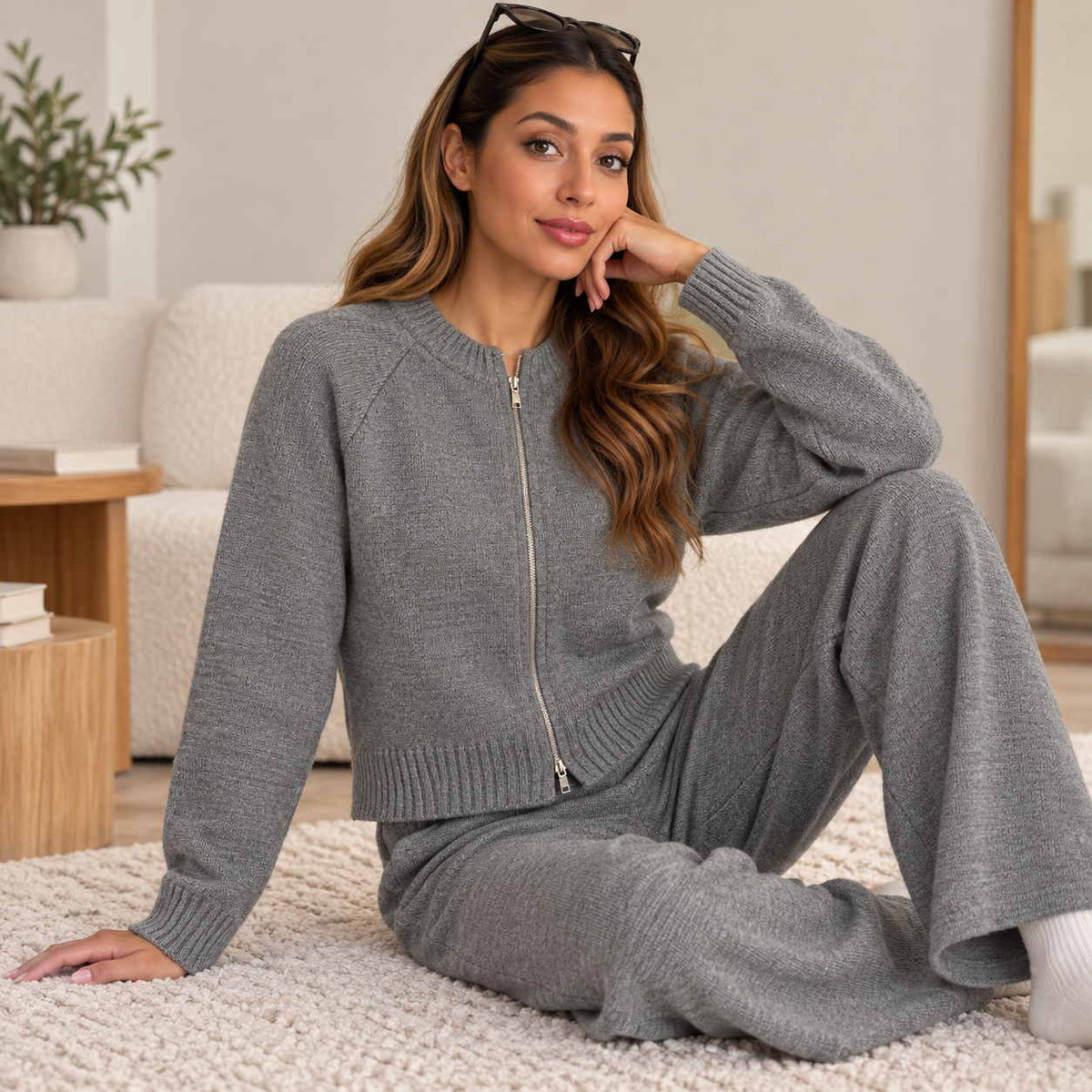 Grey zip up knit cardigan and wide leg pants set, worn sitting on a cream rug with sunglasses on her head