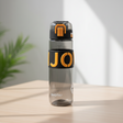 Black grip water bottle with a raised letter silicone band and a flip top lock lid
