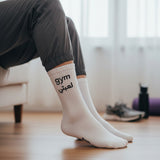 Person wearing white socks with 'gym' text in a home setting
