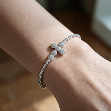 Silver tennis bracelet with a halo crystal cross worn on a raised wrist by a window