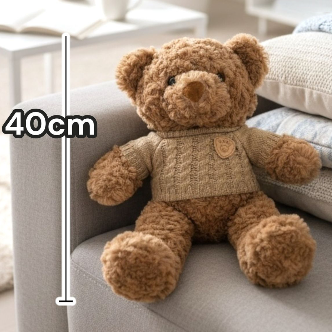 Caramel boucle bear in a sand cable knit jumper sitting against stacked cushions