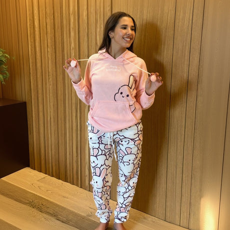 Woman wearing a pink hoodie and bunny-patterned pyjama pants with a relaxed fit for winter comfort